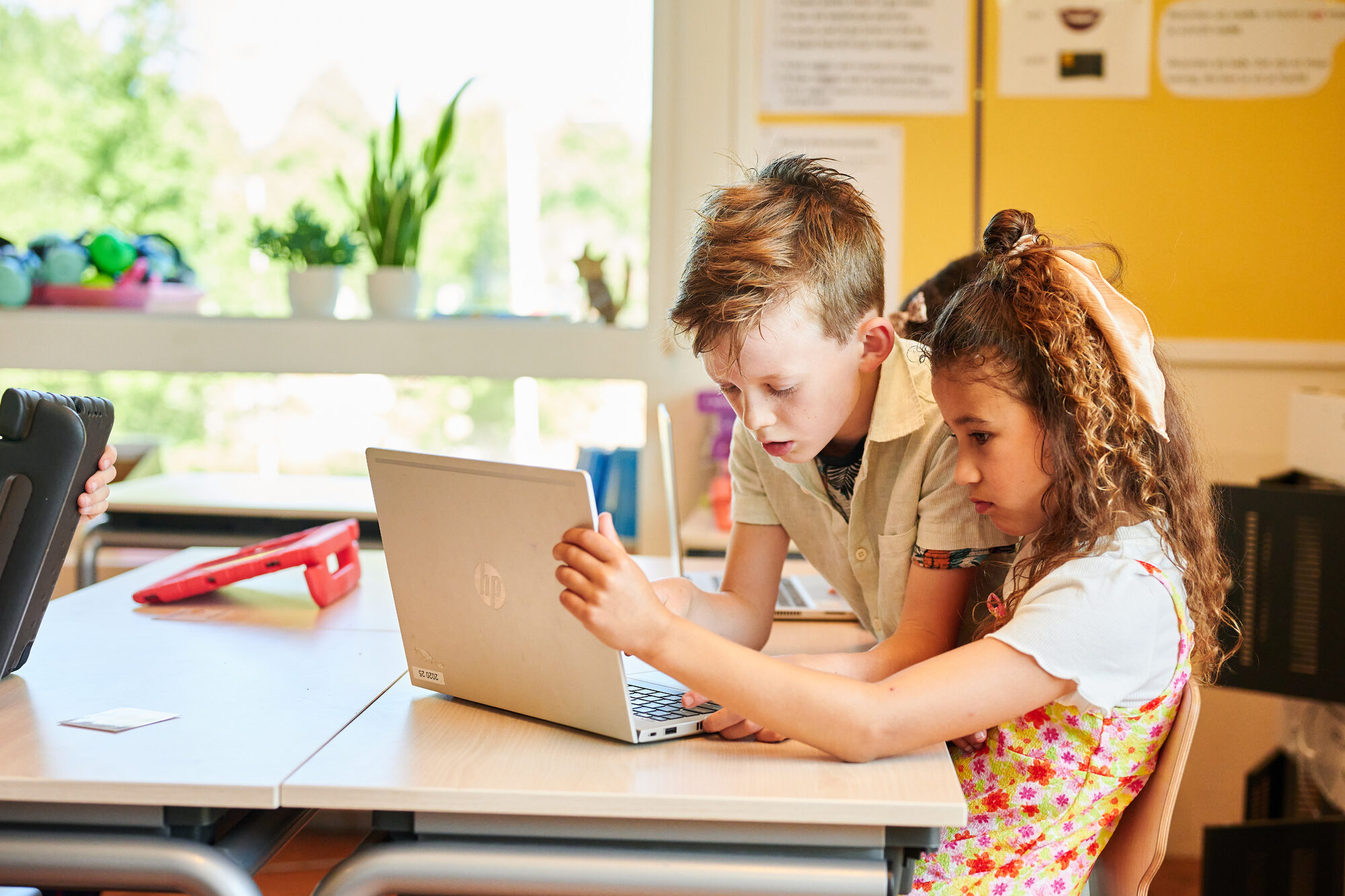 Leerlingen achter een laptop helpen elkaar